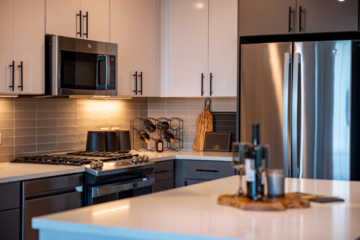 Madison West Elm apartments Modern kitchen with stainless steel appliances, white cabinets, and a wine rack on the counter.