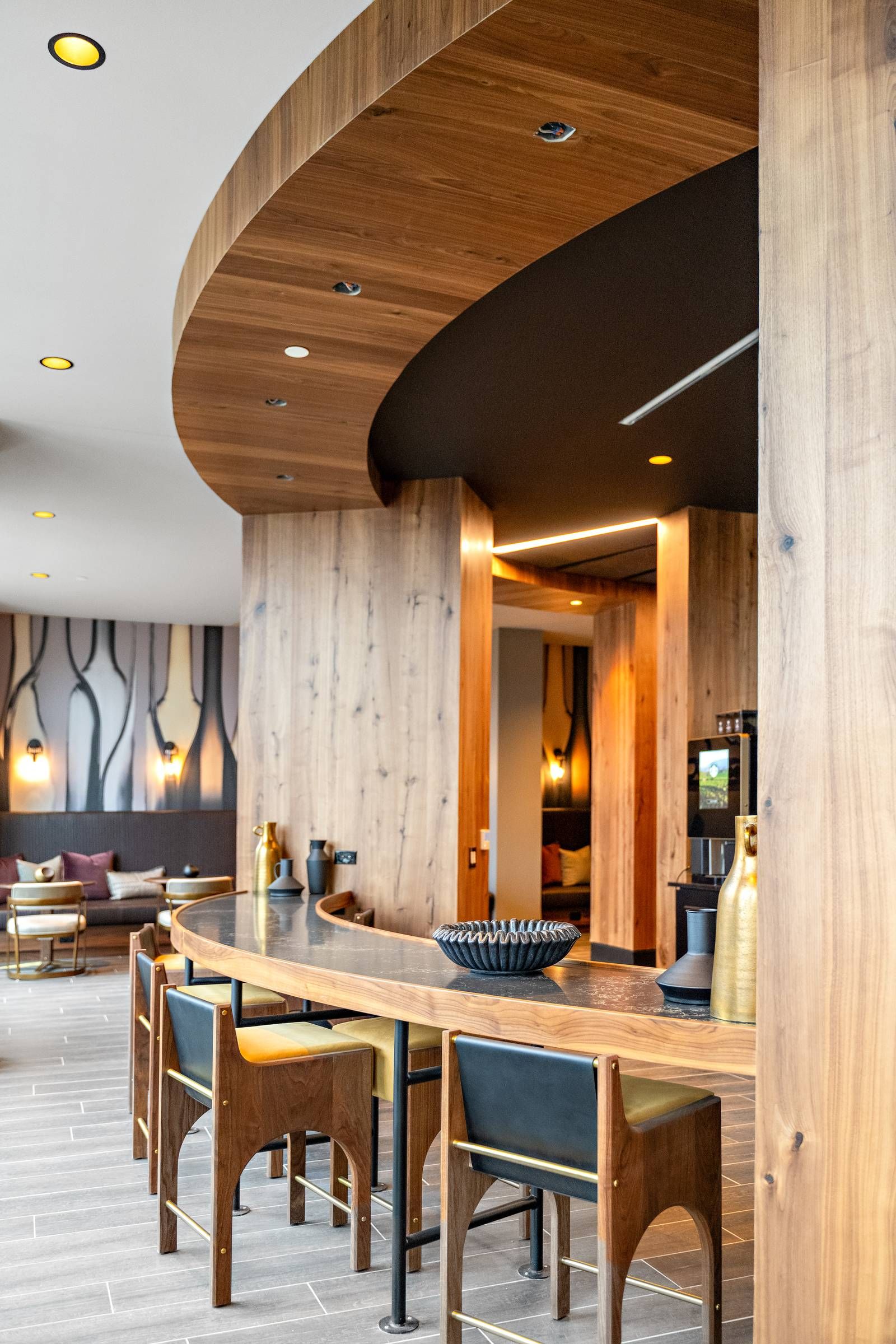 Madison West Elm apartments Modern lounge with wooden décor, curved ceiling, bar seating, and soft lighting in a stylish, contemporary setting.